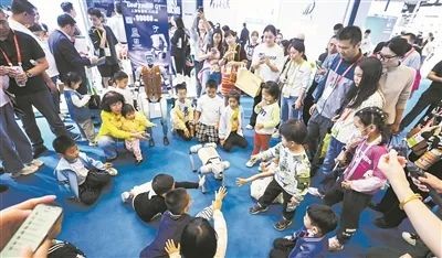 4月13日,在第五届消博会现场,小朋友和宇树科技展示的机器狗互动。新华社记者 杨冠宇摄